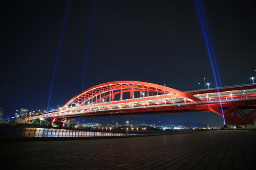 赤くライトアップした神戸大橋と夜空に伸びるレーザービーム