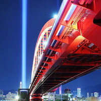 見上げた神戸大橋とレーザービーム 赤と青でライトアップされた夜景の写真