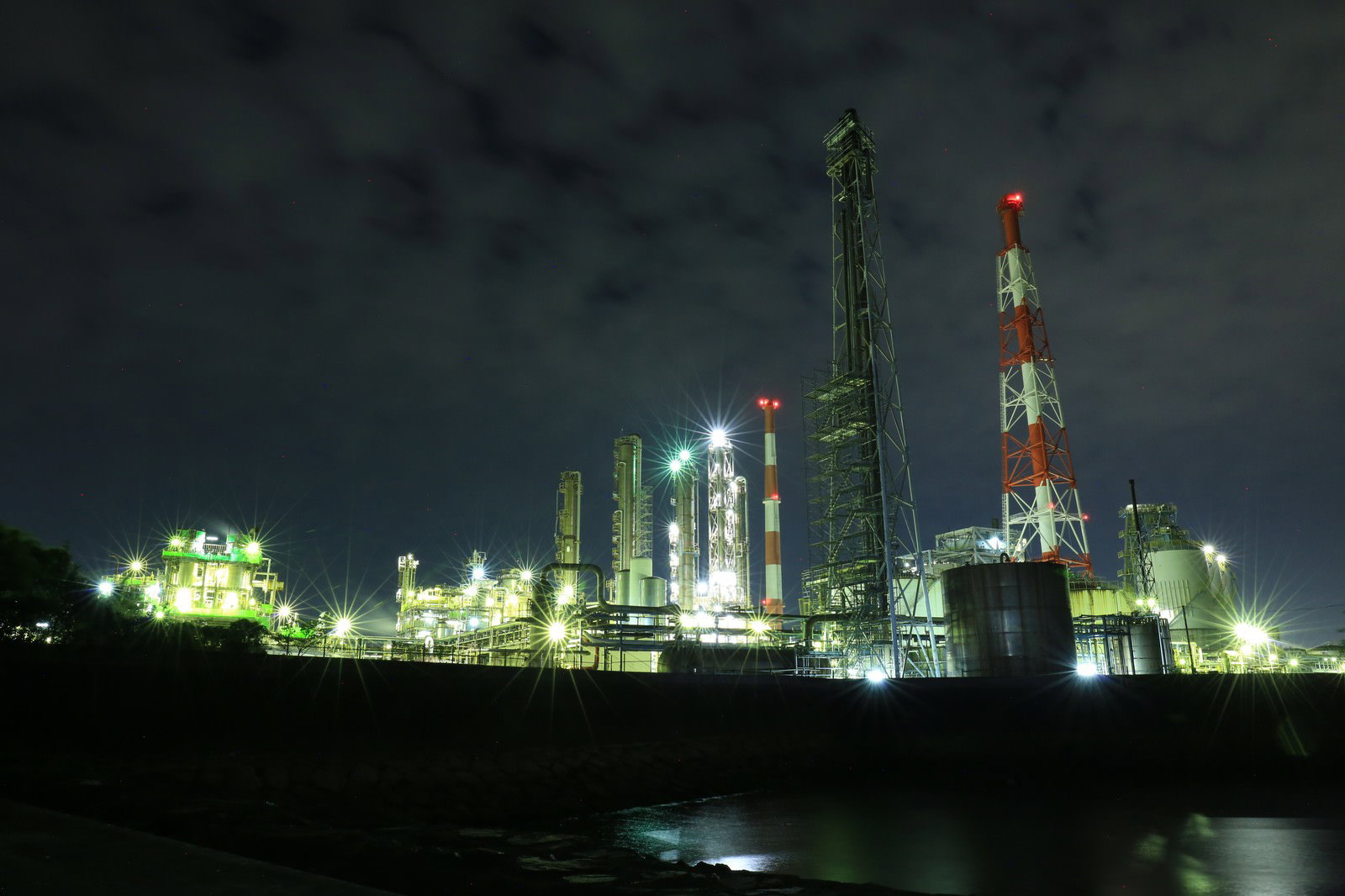 煙突と光芒が広がる工場夜景