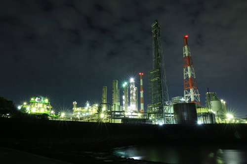 夜間にライトアップされた工場プラントと光芒の夜景