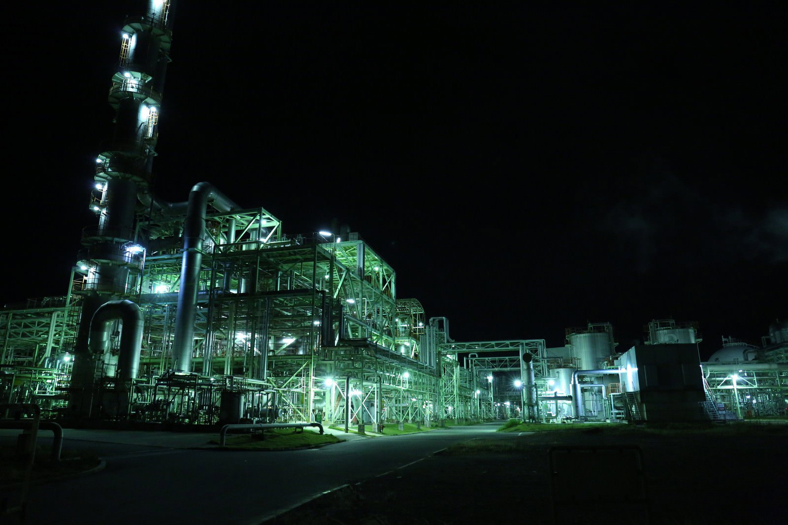 暗闇の中で緑色の照明に照らされた工場の夜景