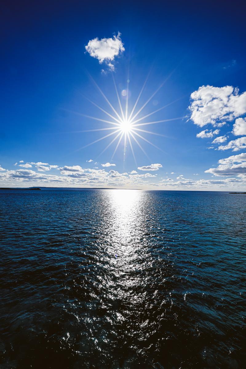 太陽の光芒が海面に輝く、青い空と青い海の風景