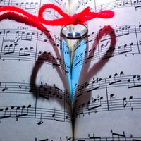 楽譜に伸びたハートと運命の赤い糸、指輪が彩る愛情の表現の写真