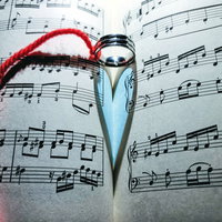 指輪に結ばれた赤い糸と楽譜の影が作るハートの写真