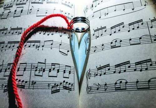 指輪に結ばれた赤い糸と楽譜の影が作るハート