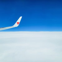 青空と雲海の上を飛ぶ飛行機の翼の写真