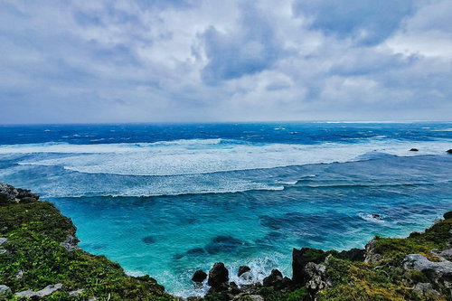 宮古島の海岸から望む白い波と青い海の写真