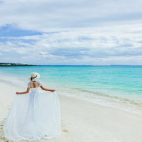 宮古島の透き通った海を背に白いドレスを翻す女性の写真