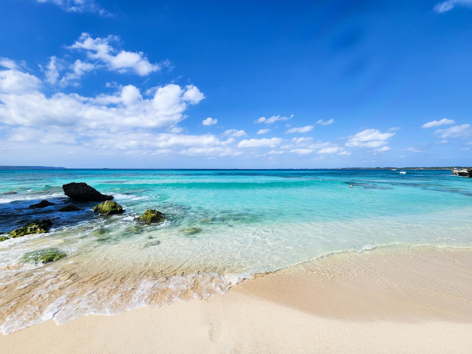 宮古島の宮古ブルーの海と白い砂浜に打ち寄せる波と岩