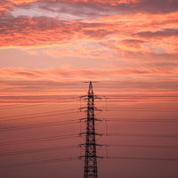 夕焼けに染まる雲と鉄塔のシルエットの写真