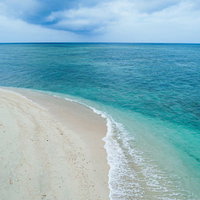 エメラルドグリーンに広がる透明な海と白い砂浜の写真