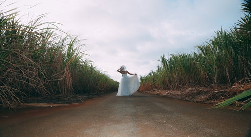 緑の南国リゾートの道を歩くウェディングドレスの女性