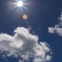 真夏の光芒とパラシュートが映える青空と白い雲の写真