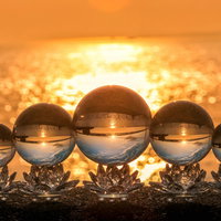 海岸に並ぶ水晶玉に映る夕景と光芒、夕日が作る虹色の屈折光の写真