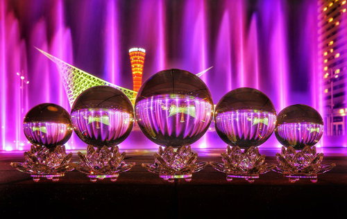 紫色の光でライトアップされた噴水を映し込む水晶玉