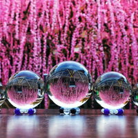 ピンク色の枝垂れ梅を背景に並ぶ透明なガラス玉と水晶玉の写真