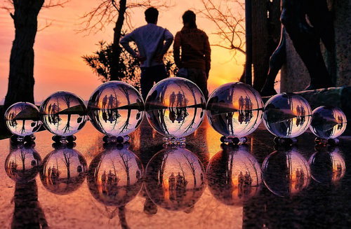 ガラス玉越しに映る夕焼けと二人組のリフレクション