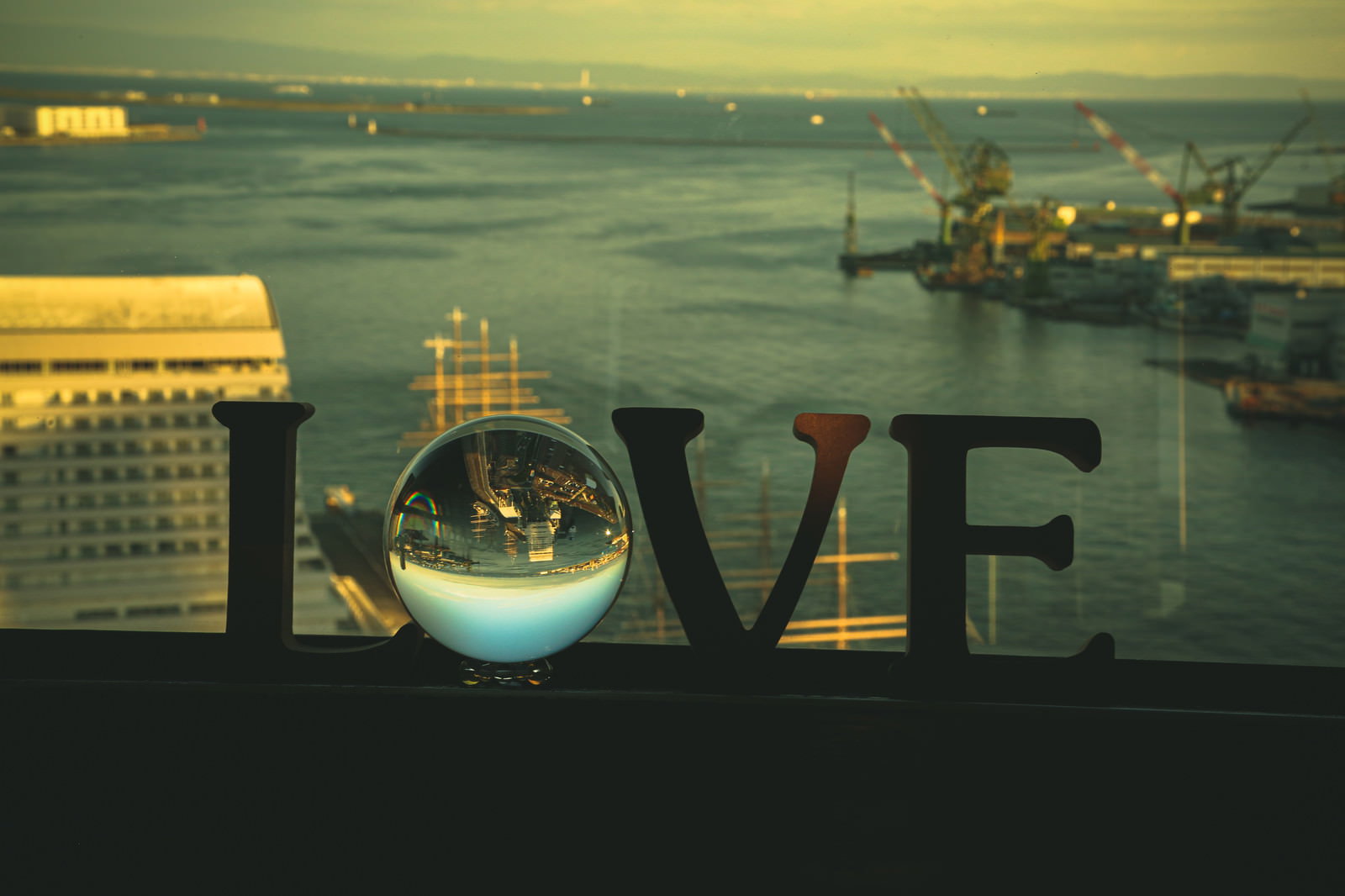 LOVEの文字が入ったガラス玉越しに見える夕焼けの埠頭風景