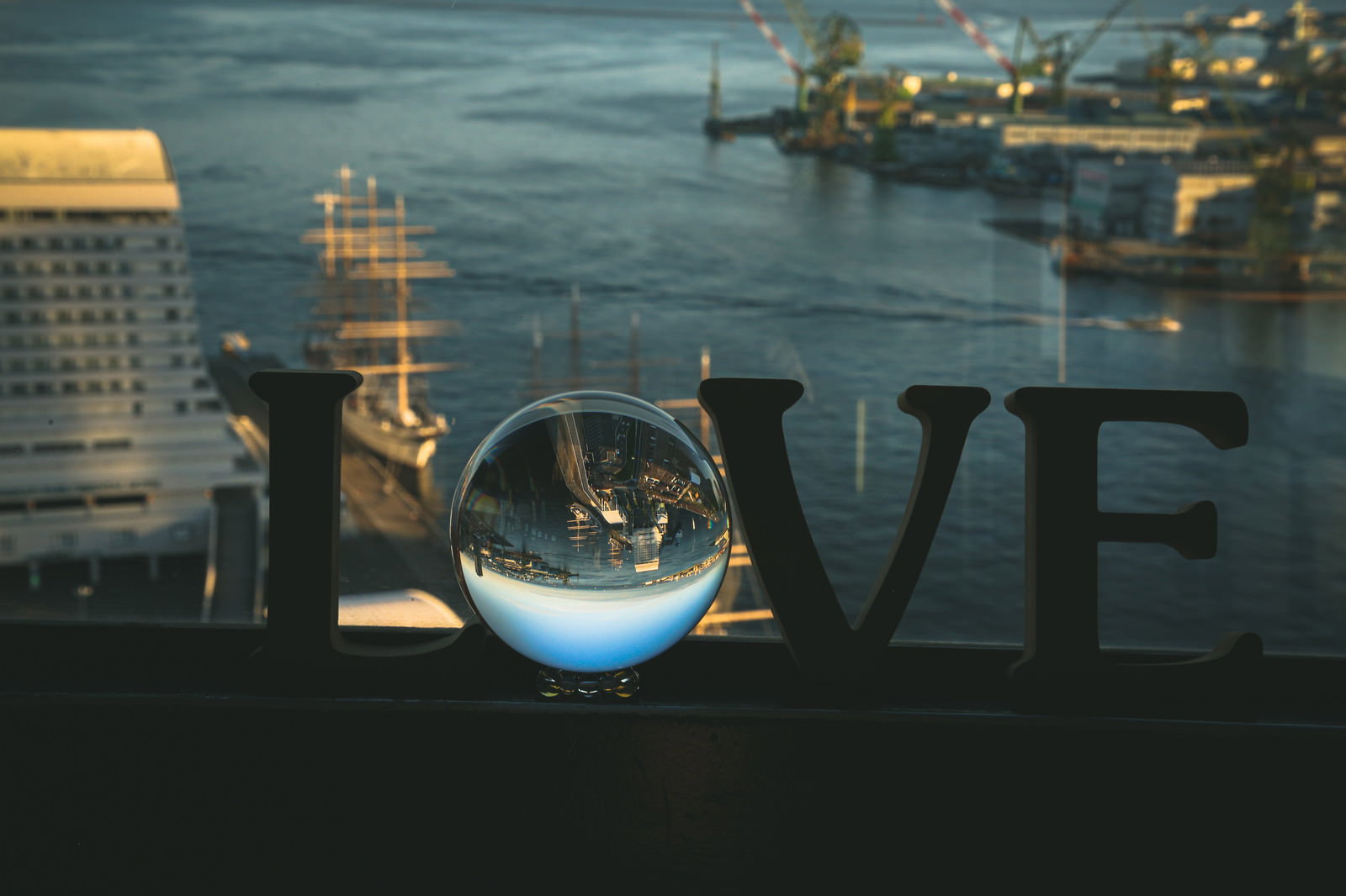 夕暮れの港でガラス玉に包まれたLOVEの文字と水晶玉