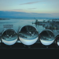 埠頭に一列に並ぶ水晶玉と朝焼けの海の写真