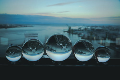 埠頭に一列に並ぶ水晶玉と朝焼けの海