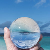水晶玉に反転して映り込む南国のエメラルドグリーンの海の写真