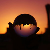 手に持つ水晶玉と夕焼けのシルエット、逆光に映る夕景の写真