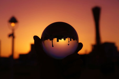 手に持つ水晶玉と夕焼けのシルエット、逆光に映る夕景