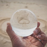 砂浜で手のひらに乗せた水晶玉に映り込む逆ハートの写真