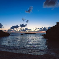 岩に囲まれた海岸の日没時の風景 - 夕焼けの美しい海の風景の写真