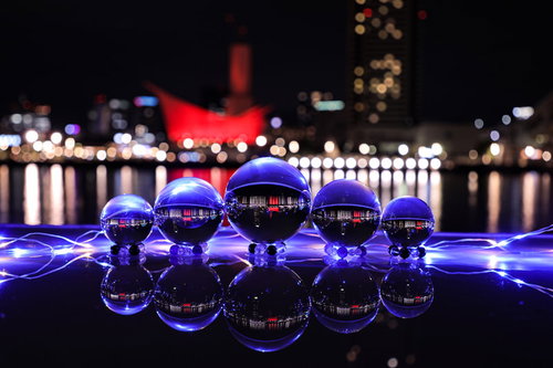 紫色の光に包まれた兵庫の夜景を映す水晶玉