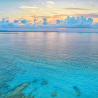 日暮れのオレンジの空と静かな宮古島の海に浮かぶ白い積雲の写真