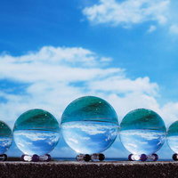 ガラス玉を通して見た宮古島の青い空と雲、透明な球面に映り込む海景色の写真