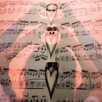 楽譜に映るハートの影とハートのハンドサインの写真