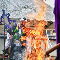 オレンジ色の炎の中でお焚き上げを執り行う住職の写真