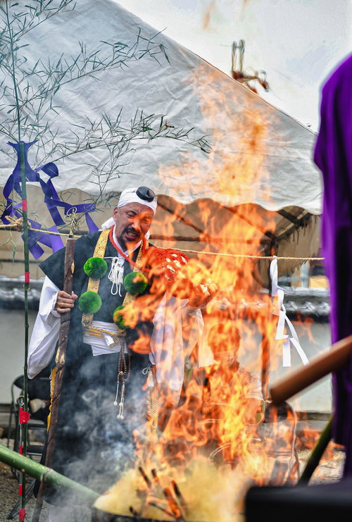 オレンジ色の炎の中でお焚き上げを執り行う住職