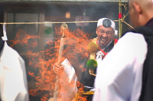 大声で節を付けて般若心経を唱えながらお焚き上げをする行者