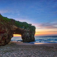 宮古島の砂山ビーチで夕焼けに照らされるアーチ岩の写真