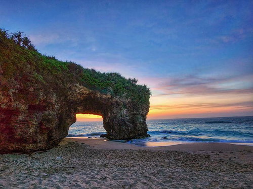 宮古島の砂山ビーチで夕焼けに照らされるアーチ岩
