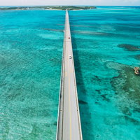 池間大橋を行き交う車と透き通るターコイズブルーの海の写真