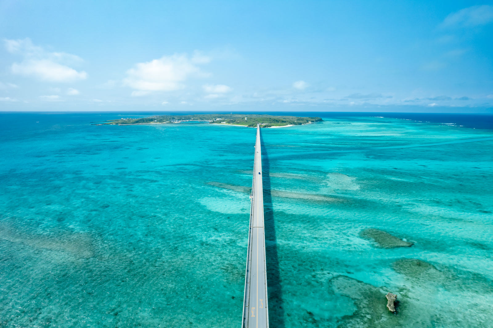 ターコイズブルーの海に架かる池間大橋と島を見る空撮