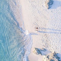 ムスヌン浜の波打ち際を歩く観光客ふたり、宮古ブルーの海の写真