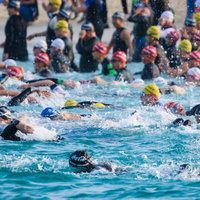 海上でレースを繰り広げるトライアスロン選手たちの写真