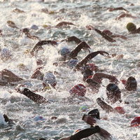 トライアスロンのスイムで激しく競う選手達と立ち上がる水しぶきの写真