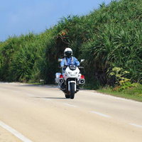 三角点付近の田舎道をパトロールする白バイの写真