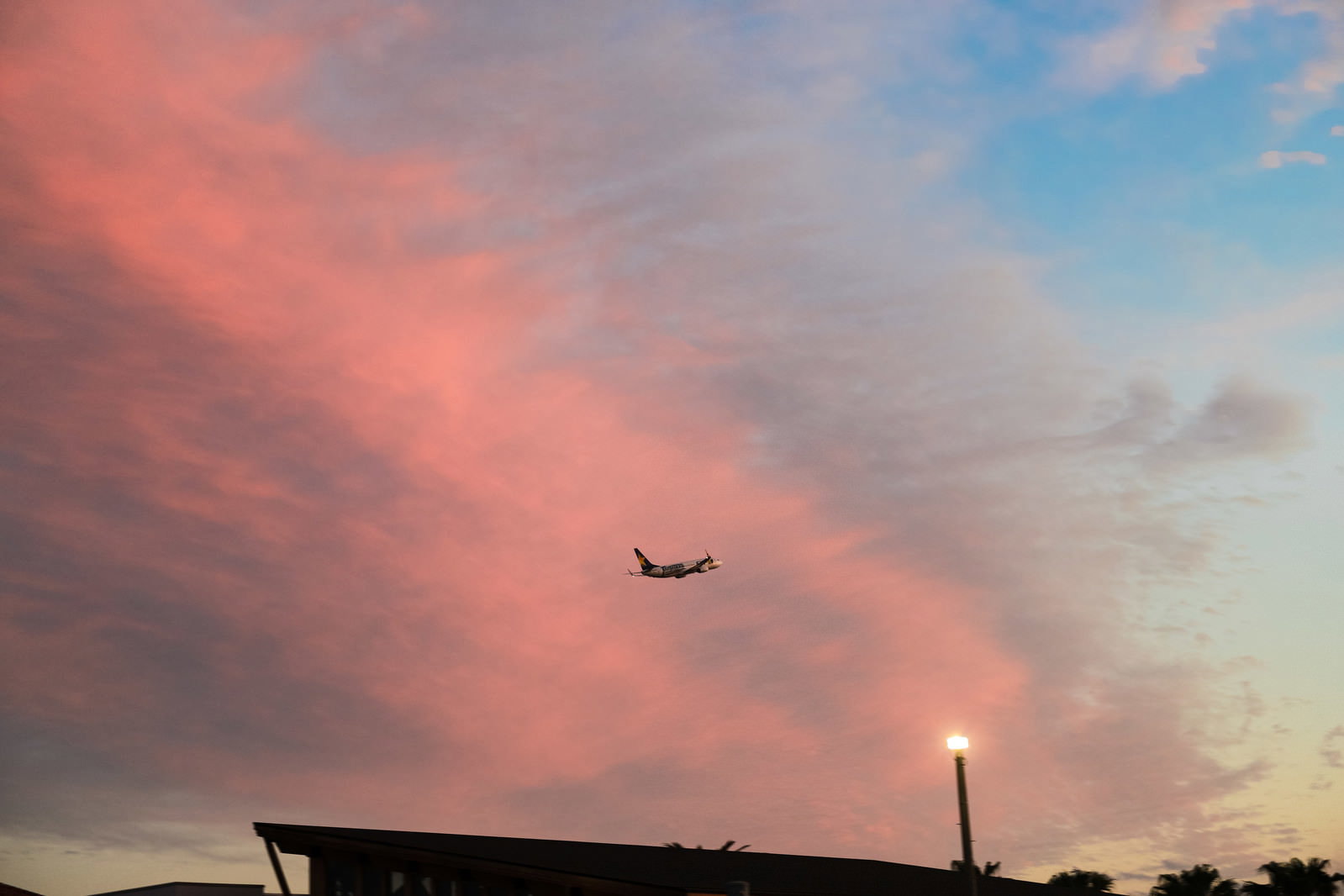 オレンジ色の夕焼け雲が広がる空を飛行する旅客機のシルエット