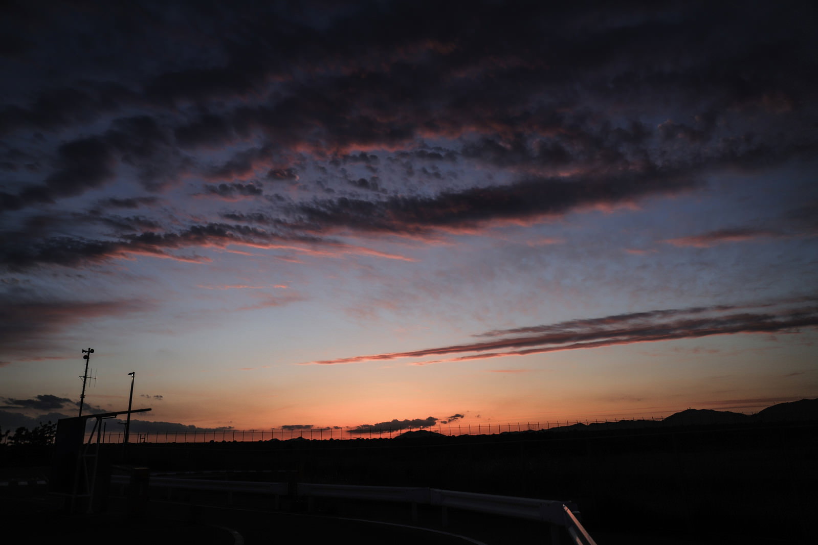 日没前の空がオレンジとピンクに染まり雲が広がる夕焼けの風景