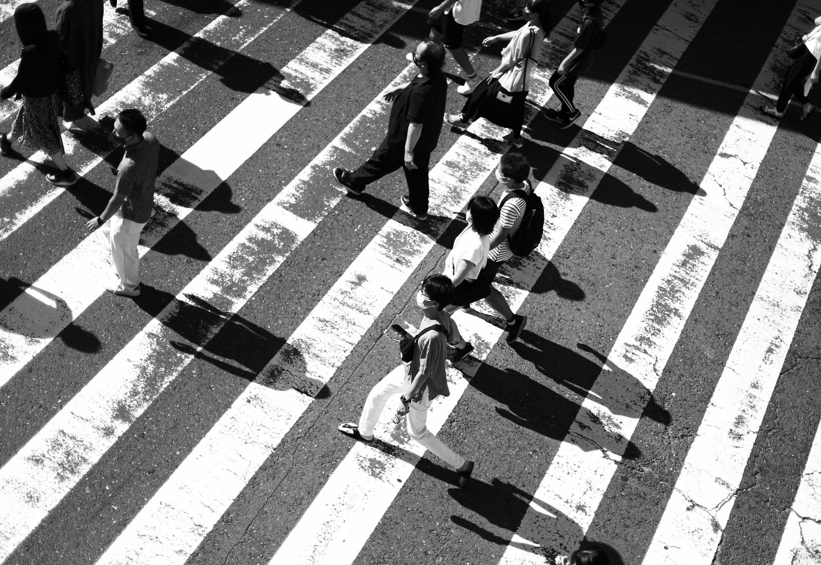 横断歩道を上から見下ろした白黒写真で複数の人が歩いている様子