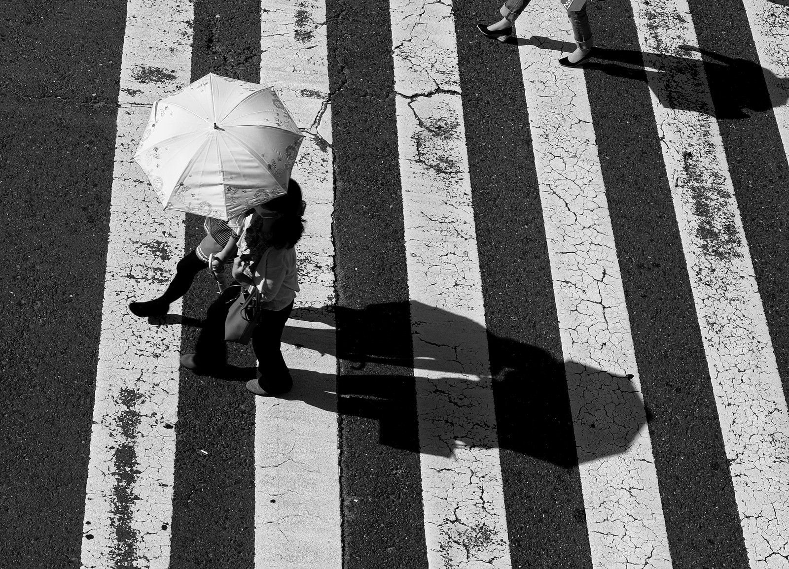 横断歩道を渡る日傘を差したカップルのモノクロ写真