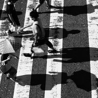 白黒の横断歩道を渡る人影、縞模様の道路上で交通する都市風景の写真